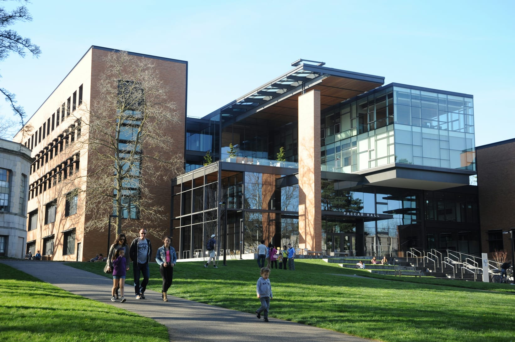A modern school campus building with lawns and students walking along the path outside.